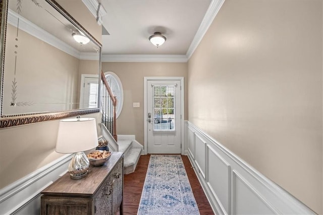 entryway featuring ornamental molding, dark wood finished floors, wainscoting, and a decorative wall