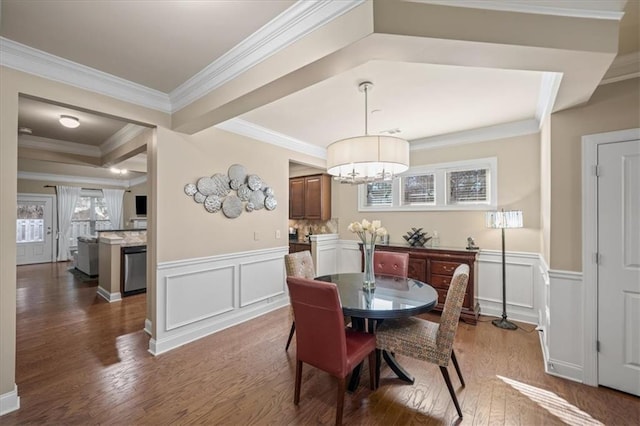 dining room featuring a wainscoted wall, crown molding, a decorative wall, and wood finished floors