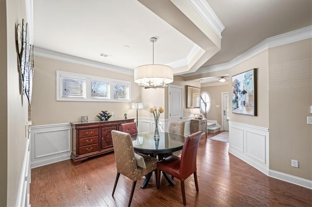 dining area with crown molding, a wainscoted wall, visible vents, and dark wood finished floors