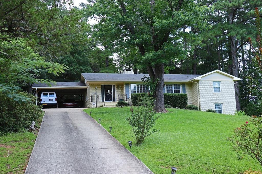 view of front of home featuring a front yard, brick siding, driveway, and an attached carport