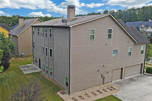 rear view of house with a garage, central AC, and a lawn