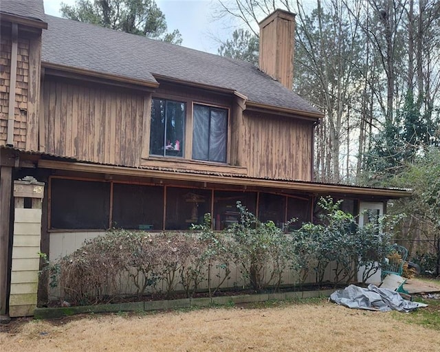 view of property exterior featuring a shingled roof, a lawn, and a chimney