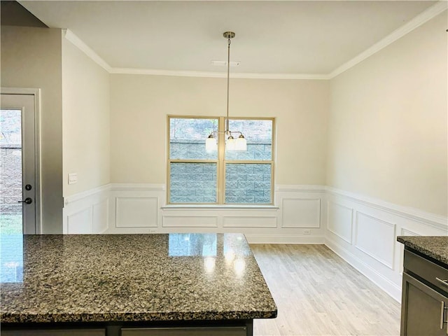 unfurnished dining area featuring a notable chandelier, light hardwood / wood-style floors, and ornamental molding