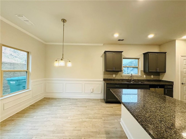 kitchen featuring light hardwood / wood-style floors, a wealth of natural light, dark stone counters, and sink