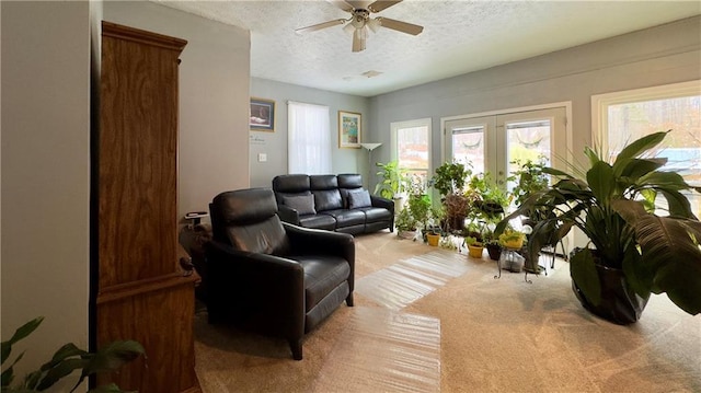 living room featuring light carpet, french doors, ceiling fan, and a textured ceiling