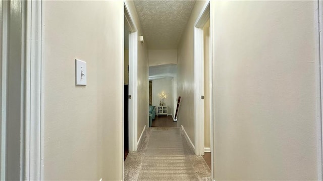 hallway with carpet flooring and a textured ceiling