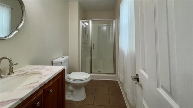 bathroom featuring tile patterned flooring, vanity, a shower with shower door, and toilet