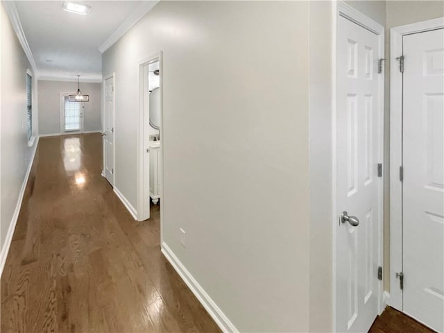 corridor with baseboards, wood finished floors, and ornamental molding