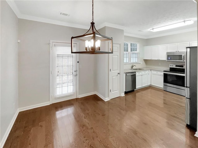 kitchen with wood finished floors, visible vents, a sink, stainless steel appliances, and a notable chandelier