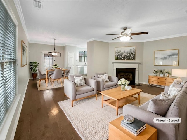 living area featuring visible vents, a fireplace with flush hearth, a ceiling fan, wood finished floors, and crown molding