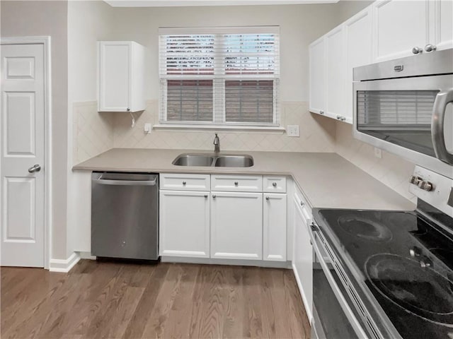 kitchen featuring light wood finished floors, light countertops, appliances with stainless steel finishes, white cabinets, and a sink