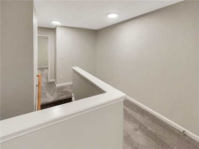 hallway with baseboards, an upstairs landing, and carpet floors