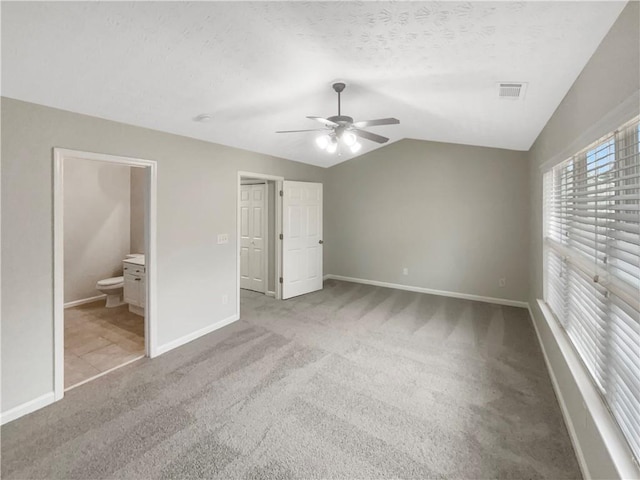 unfurnished bedroom with baseboards, visible vents, lofted ceiling, a textured ceiling, and carpet flooring