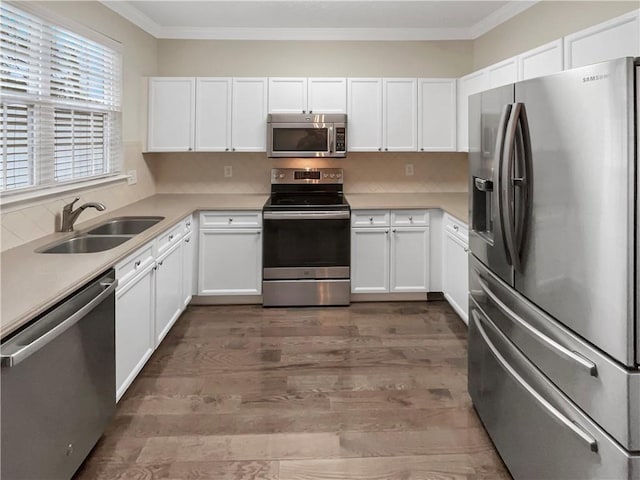 kitchen with a sink, stainless steel appliances, crown molding, and white cabinetry