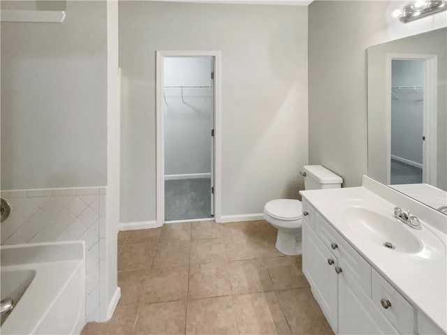 bathroom featuring toilet, vanity, tile patterned flooring, a bath, and a spacious closet