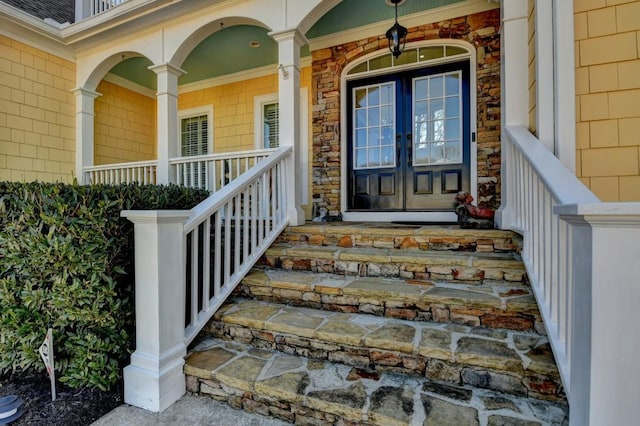 property entrance with french doors, a porch, and roof with shingles