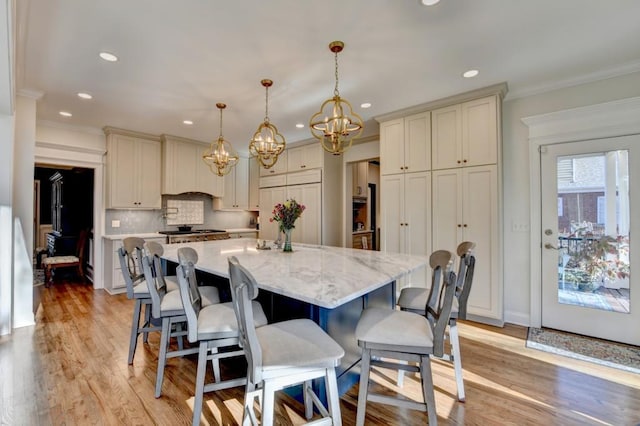 kitchen with ornamental molding, light wood-type flooring, paneled built in fridge, and tasteful backsplash