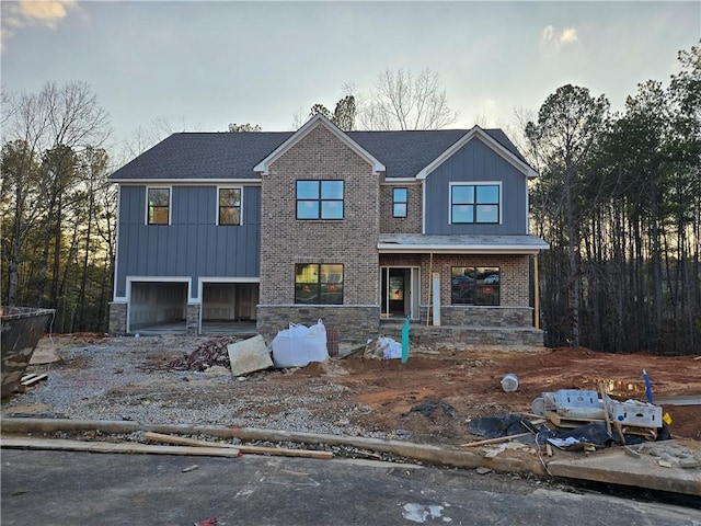 view of front of house with board and batten siding, stone siding, brick siding, and a garage