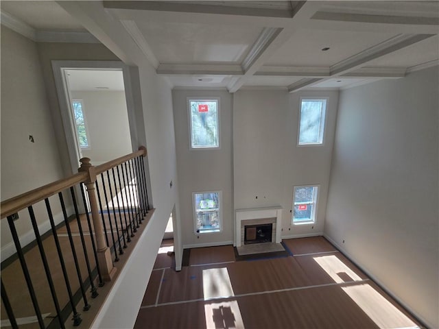 unfurnished living room with baseboards, coffered ceiling, a fireplace, and beamed ceiling