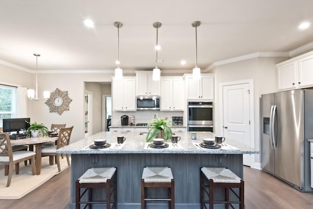 kitchen with stainless steel appliances, white cabinetry, ornamental molding, and a kitchen bar