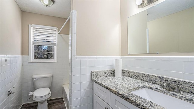 full bathroom with toilet, hardwood / wood-style floors, tile walls, shower / tub combination, and vanity