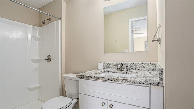 bathroom featuring toilet, a shower, and vanity