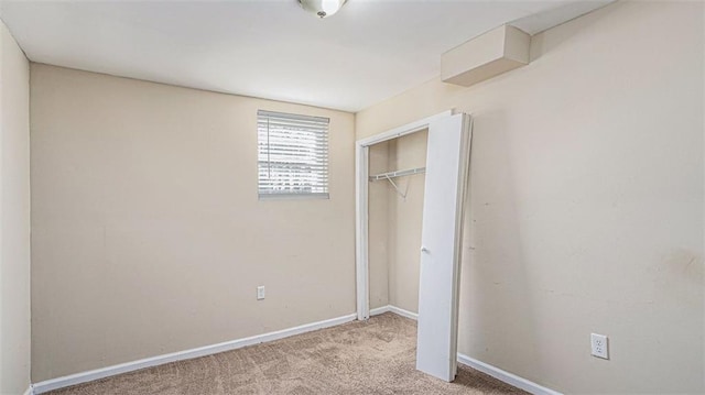 unfurnished bedroom with light colored carpet and a closet