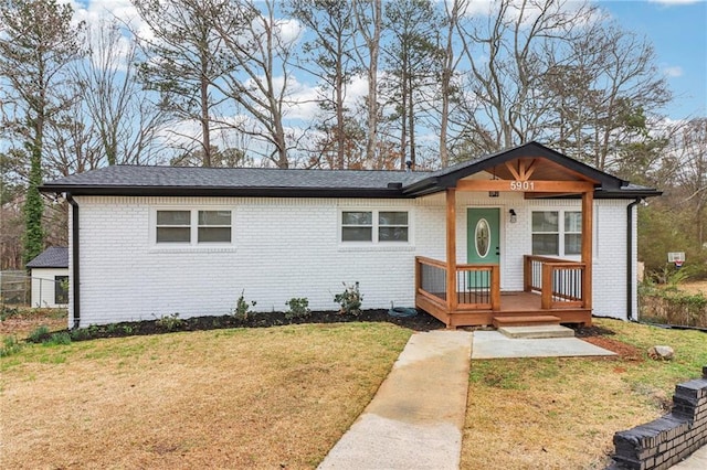 view of front of house with a front yard, covered porch, and brick siding