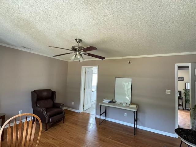 sitting room featuring a textured ceiling, hardwood / wood-style floors, ornamental molding, and ceiling fan