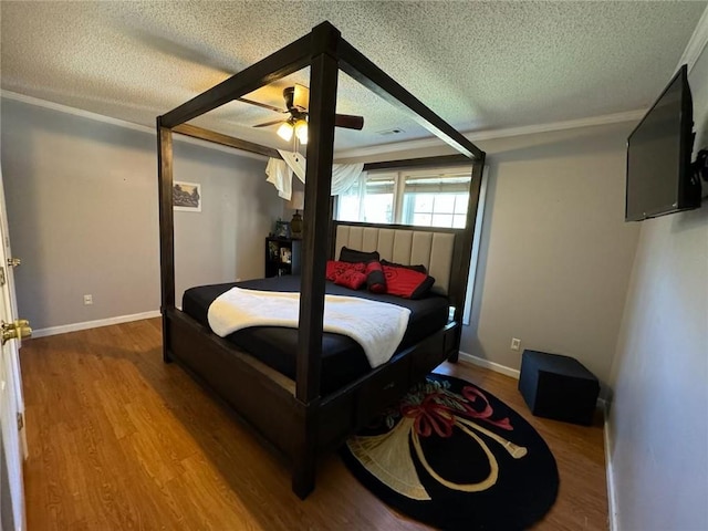 bedroom featuring hardwood / wood-style flooring, a textured ceiling, ornamental molding, and ceiling fan