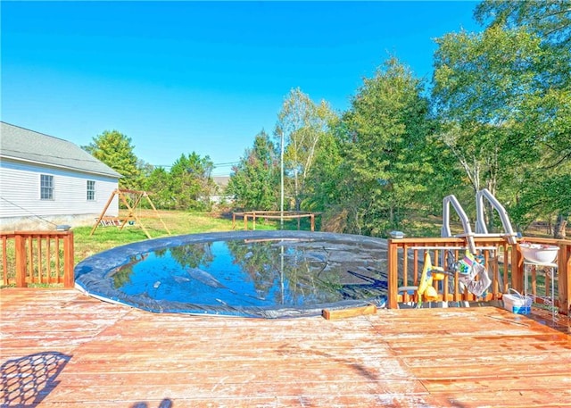 view of pool with a playground and a wooden deck