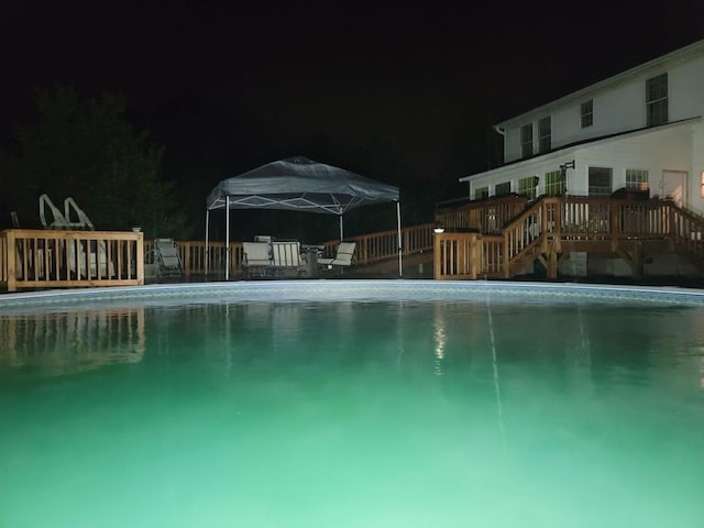 pool at night with a deck and a gazebo