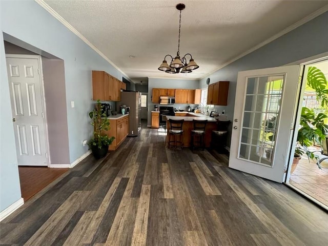 dining room with dark wood-type flooring, a textured ceiling, a notable chandelier, and ornamental molding