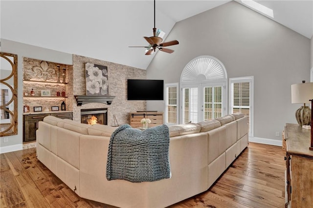 1313 Fallsbrook Ter NW, Acworth, GA 30101 - living area with high vaulted ceiling, light wood-type flooring, a ceiling fan, a large fireplace, and a skylight
