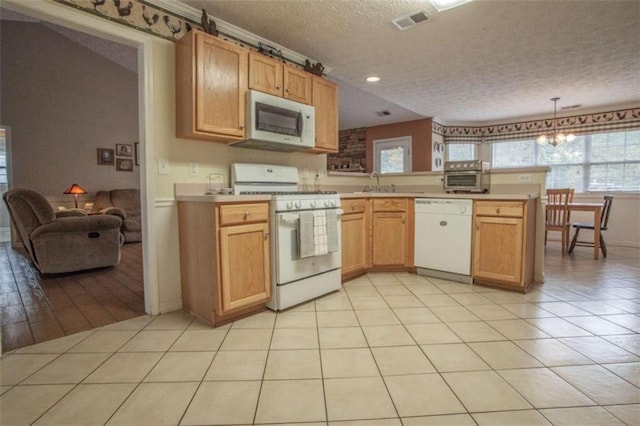 kitchen with kitchen peninsula, a textured ceiling, light tile patterned floors, pendant lighting, and white appliances