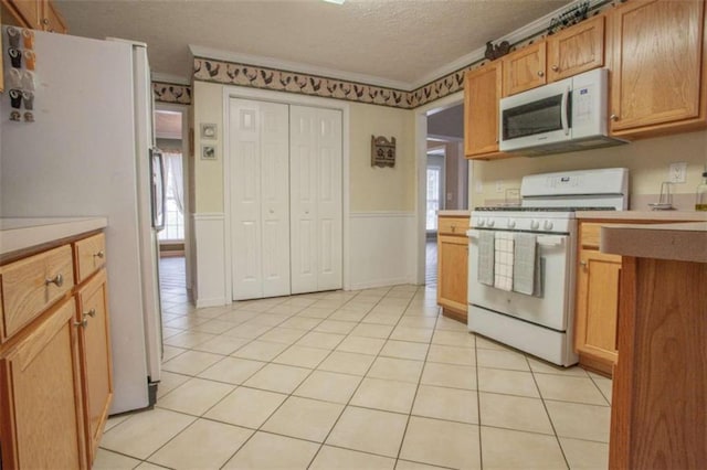 kitchen featuring white appliances, plenty of natural light, a textured ceiling, and ornamental molding