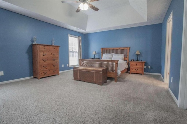 carpeted bedroom featuring ceiling fan and a tray ceiling