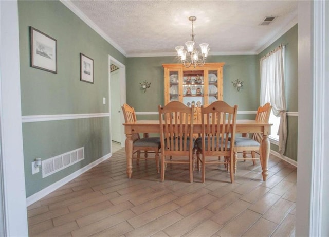 dining room with an inviting chandelier, a textured ceiling, light hardwood / wood-style flooring, and crown molding