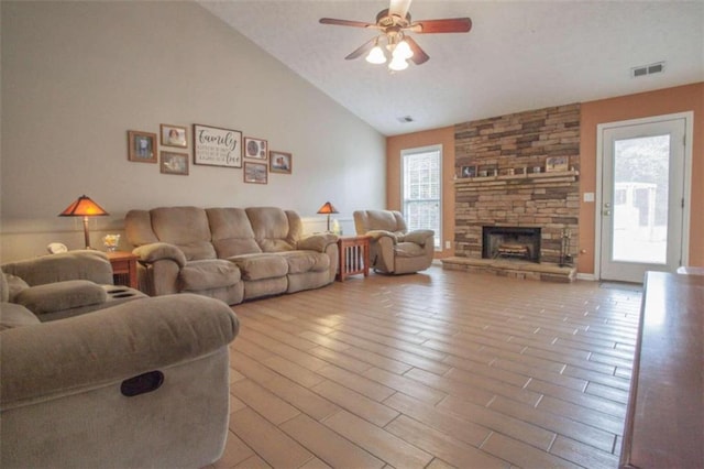 living room with a fireplace, ceiling fan, light wood-type flooring, and high vaulted ceiling