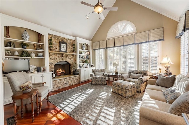 living room with a stone fireplace, built in features, high vaulted ceiling, wood-type flooring, and crown molding