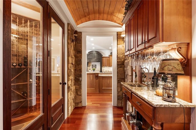 bar featuring dark wood-type flooring, sink, ornamental molding, light stone countertops, and decorative backsplash