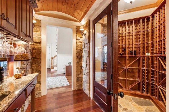 wine area with lofted ceiling, ornamental molding, and dark hardwood / wood-style flooring