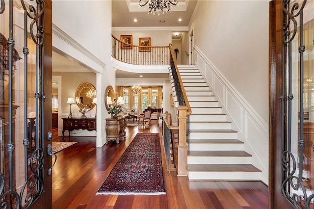 entrance foyer with crown molding, a notable chandelier, and dark hardwood / wood-style flooring