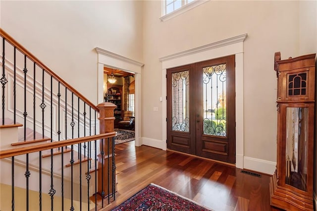 foyer entrance featuring french doors, wood-type flooring, and a high ceiling