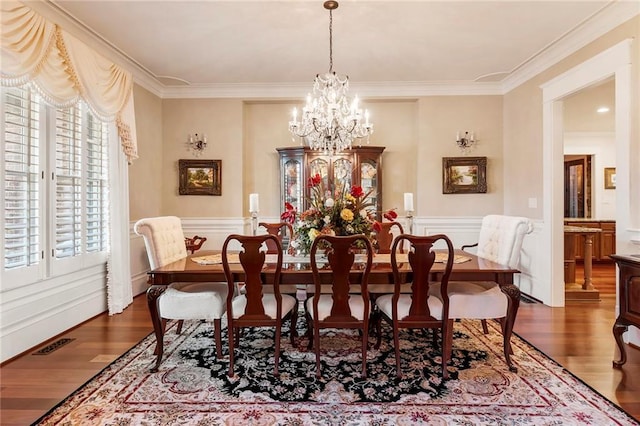 dining area featuring dark wood-type flooring, crown molding, and a notable chandelier