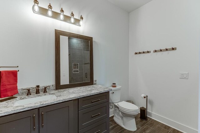 6014 Warpath Rd, Flowery Branch, GA 30542 - full bath featuring vanity, toilet, wood finish floors, baseboards, and a shower