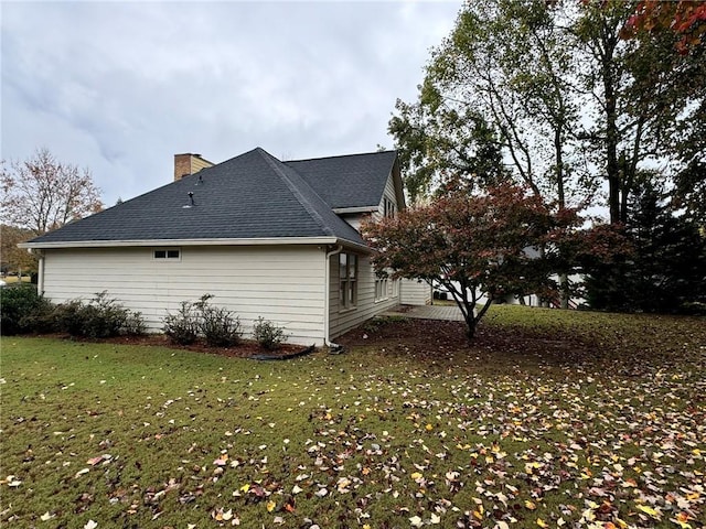 view of home's exterior with roof with shingles, a chimney, and a yard