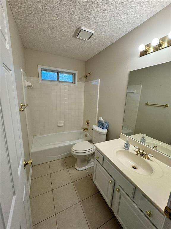 bathroom featuring toilet, tile patterned flooring, a textured ceiling, vanity, and shower / bathing tub combination