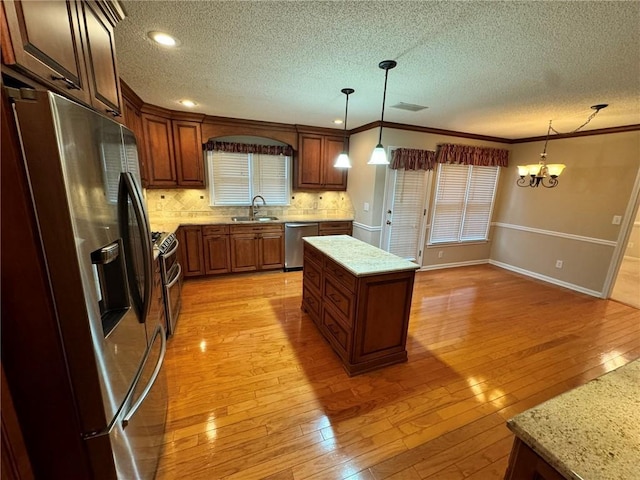 kitchen featuring stainless steel appliances, tasteful backsplash, light wood-style floors, ornamental molding, and a sink