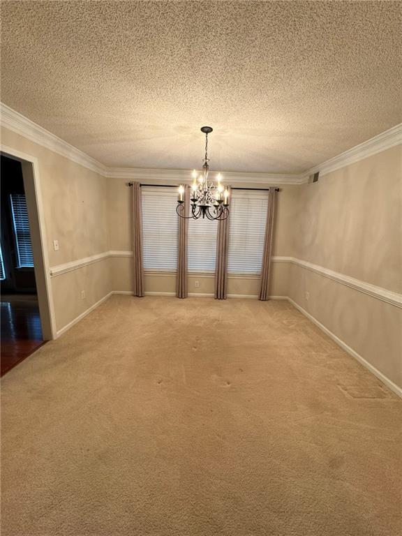 unfurnished dining area with a notable chandelier, crown molding, light carpet, and a textured ceiling